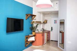 A compact kitchen with a TV mounted on the wall, a sink, and a small refrigerator. - Domus Tlv (Tel Aviv)