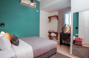 Une chambre à coucher avec un lit, un bureau, une chaise, un miroir et une fenêtre avec des rideaux.