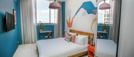 A modern bedroom with a large bed, a desk, and a chair.