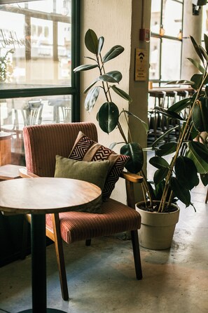 Un espace de détente intérieur, chaleureux, avec un fauteuil confortable, une table ronde et une plante en pot.