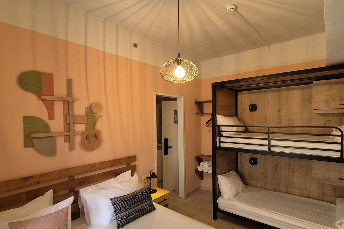 A hotel room with a bunk bed, a single bed, and a unique ceiling design.