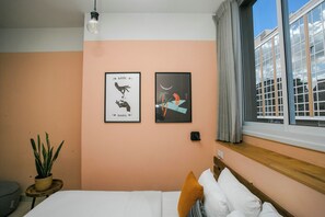 A bedroom with a bed, a potted plant, and two framed pictures on the wall. - Domus Tlv (Tel Aviv)