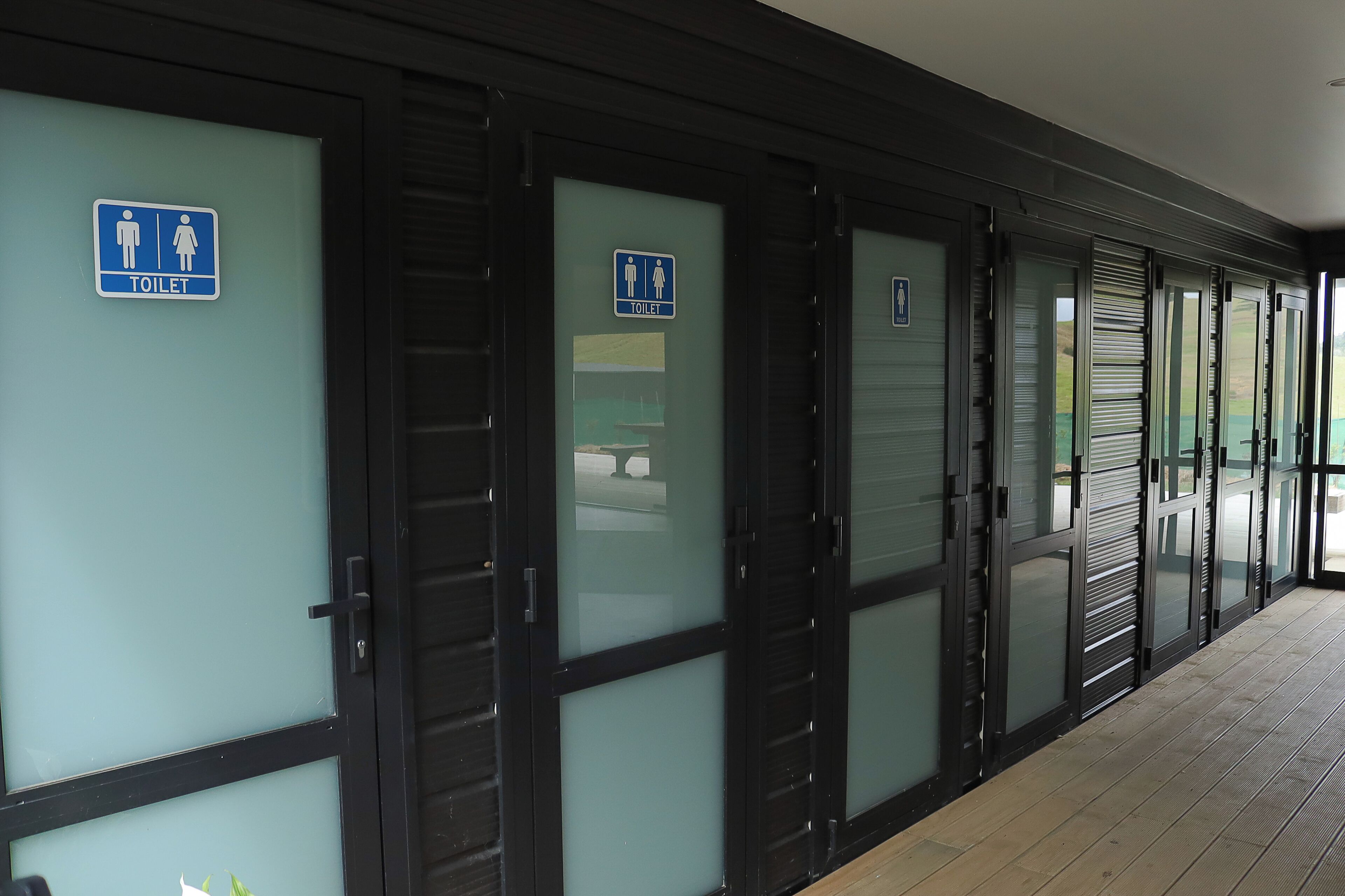A row of closed restroom doors with blue signage indicating gender-specific facilities.