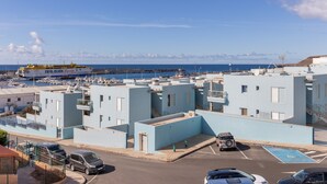 Una zona residencial costera con edificios azul claro, un puerto deportivo con barcos y un gran barco llamado 'FRED. OLSEN' al fondo.