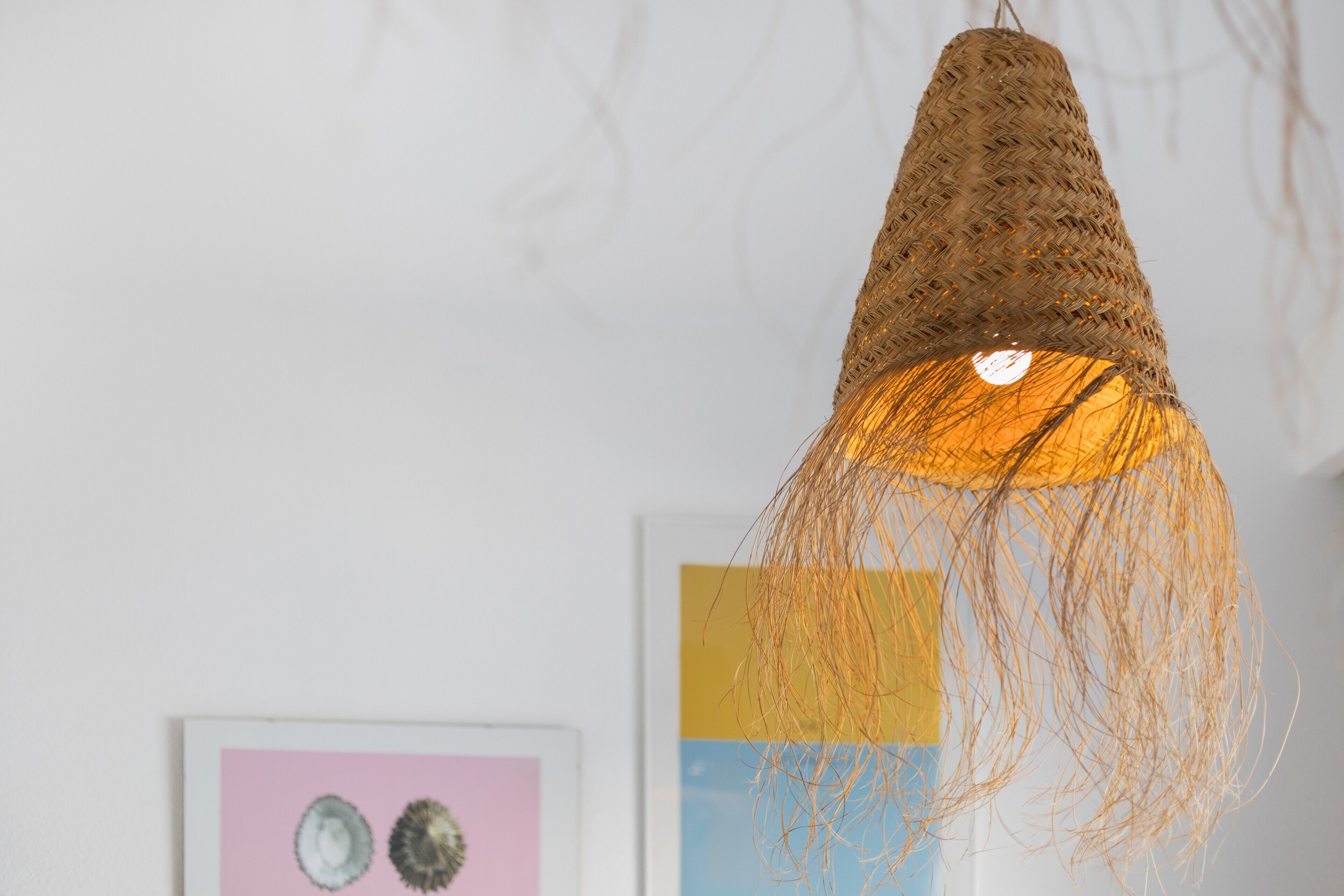A woven light fixture with a warm glow, hanging from a ceiling.