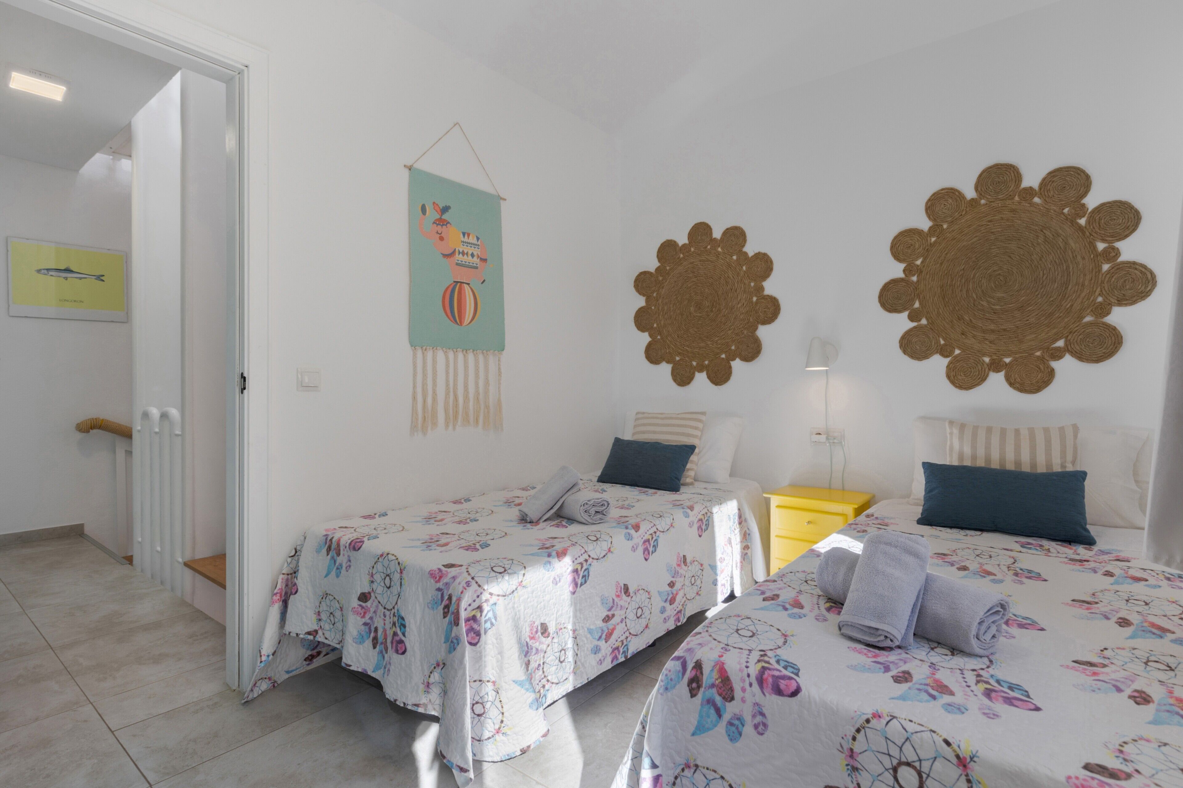 Une chambre avec deux lits, un élément de décoration suspendu et une œuvre d’art murale.