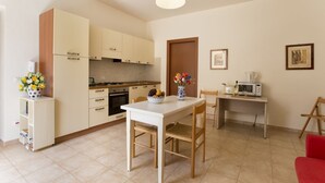 Uma cozinha compacta com área de refeições, micro-ondas e uma pequena mesa com cadeiras.