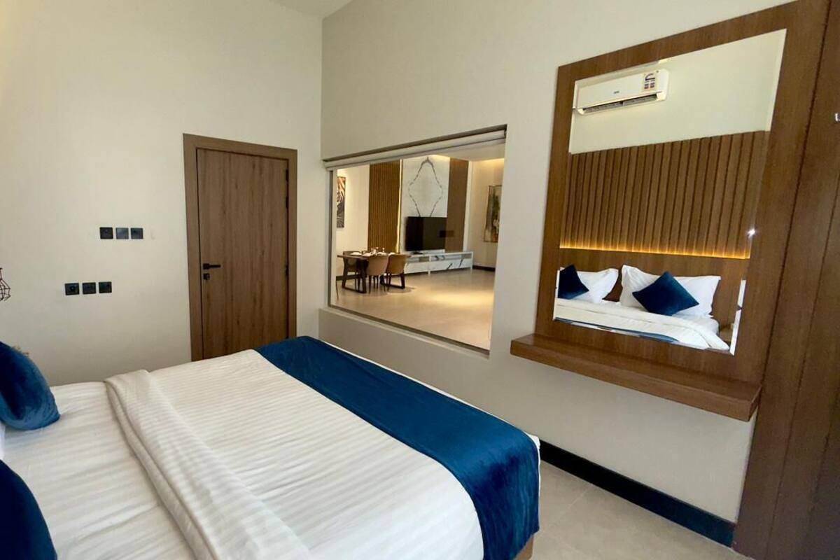 Een hotelkamer met een bed, een spiegel, een deur en uitzicht op een eetruimte.