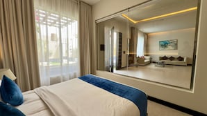 A hotel room with a large bed, a mirror, a sofa, and a view of the outside. - Lamar Park Resort  (Riyadh)