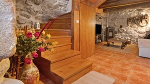 A stone wall, wooden staircase, rustic decor, and a fireplace.