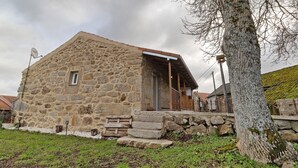 A stone building with a wooden porch, a small window, and a stone staircase leading to the entrance.