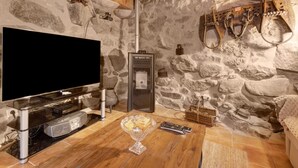 A stone-walled room with a television, fireplace, and rustic decor.