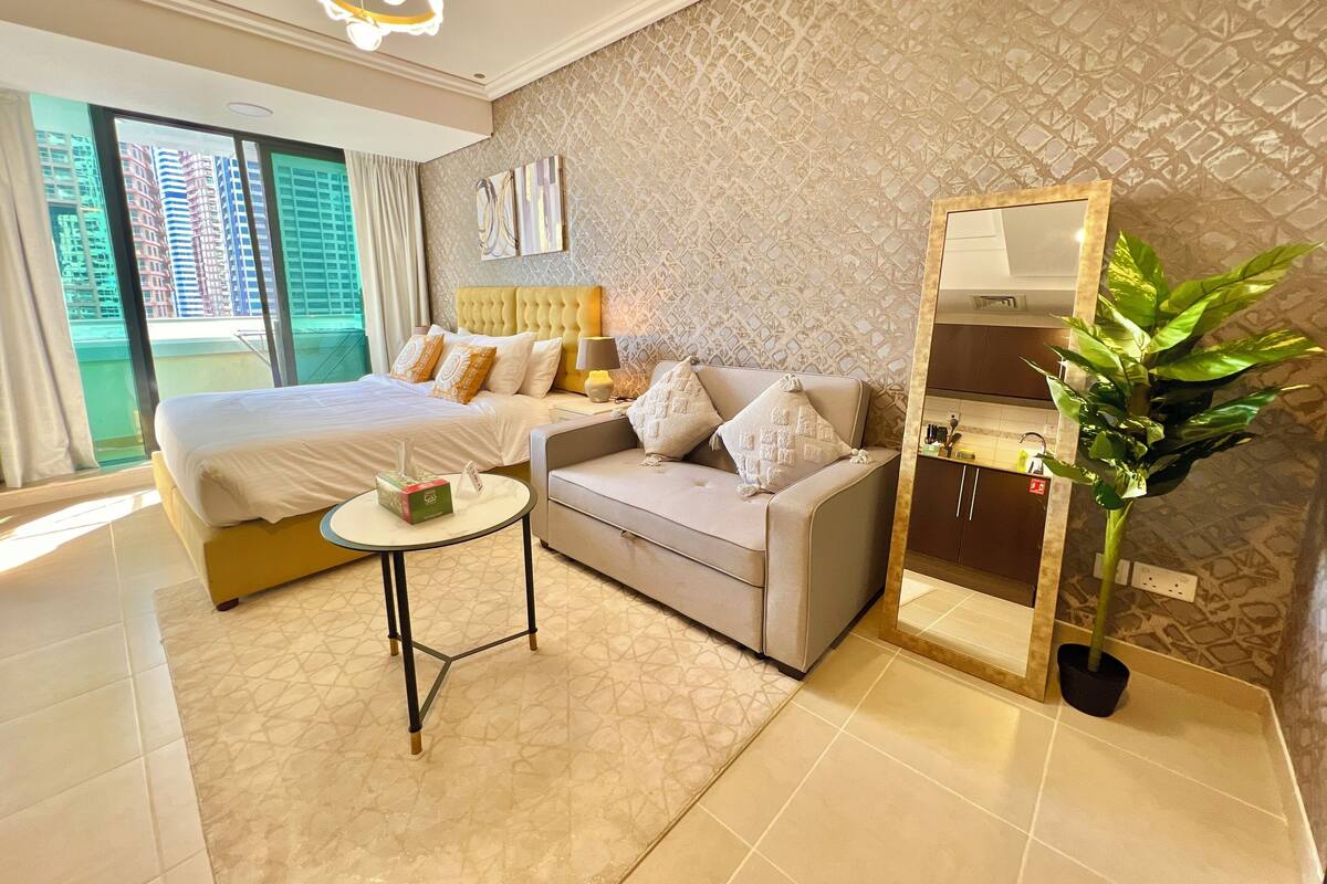 Une chambre d’hôtel moderne avec un grand lit, un canapé, une petite table et un miroir.