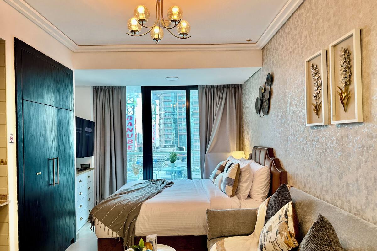 Une chambre d’hôtel moderne dotée d’un grand lit, d’un canapé, d’une télévision et offrant une vue sur le paysage urbain.