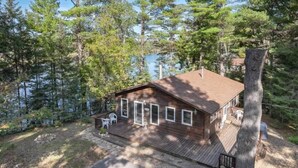 A cabin with a deck, surrounded by trees and a lake. - Eagle River Clover Pines Holiday Home (Eagle River)