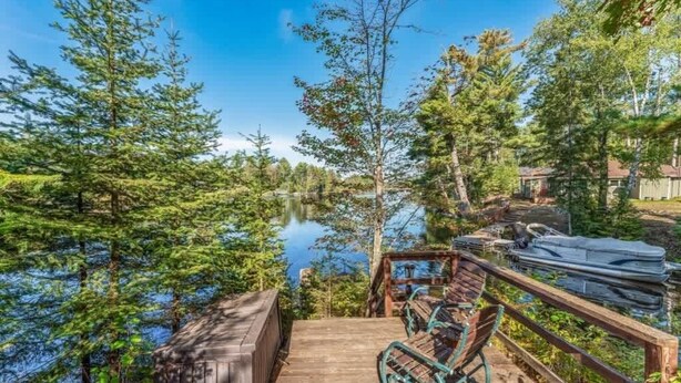 A wooden deck with a view of a lake surrounded by trees. - Eagle River Clover Pines Holiday Home (Eagle River)