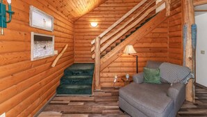 A log cabin interior with a staircase, a sofa, and a lamp. - TB-19 Thunder Bay Resort Cabin 19 (Phelps)