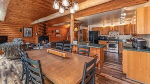 A log cabin interior with a dining area, kitchen, and a fireplace. - TB-19 Thunder Bay Resort Cabin 19 (Phelps)