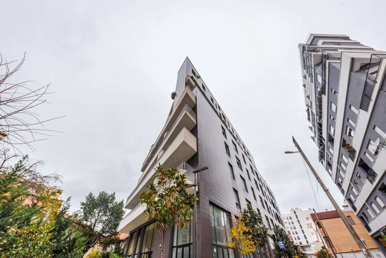 Un moderno edificio de gran altura con un diseño de esquina llamativo, ventanas amplias y balcones.