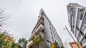 Un moderno edificio de gran altura con un diseño de esquina llamativo, ventanas amplias y balcones.
