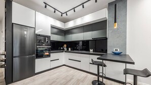 Een moderne keuken met een inbouwoven, een koelkast en een bar met barkrukken.