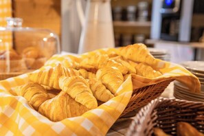 A basket of croissants on a table with a checkered cloth. - Côté Lac Hostel (Neuvecelle)