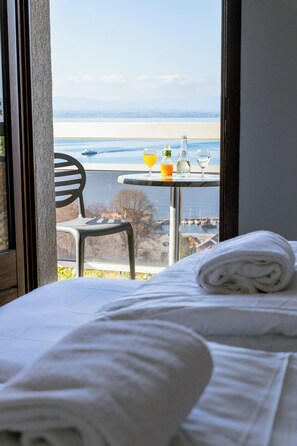 A hotel room with a bed, a chair, and a table with drinks and a bottle. - Côté Lac Hostel (Neuvecelle)