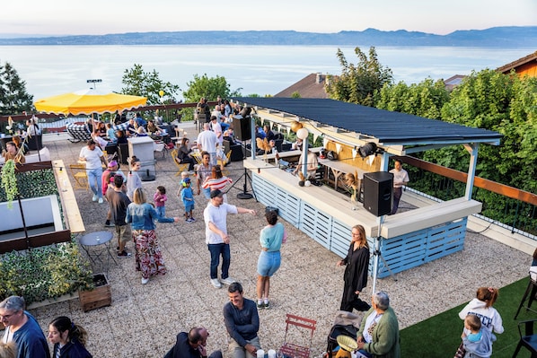 Un patio al aire libre con asientos, un escenario y vistas al lago.