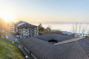 A multi-story building with a flat roof, located near a body of water. - Côté Lac Hostel (Neuvecelle)