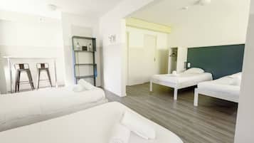 Een hotelkamer met twee bedden, een bureau, een stoel, een plank en een kledingkast.