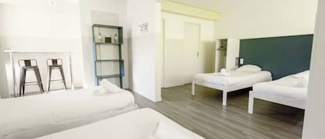 Una habitación de hotel con dos camas, un escritorio, una silla, un estante y un armario.
