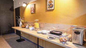 Mostrador de buffet con diversos alimentos y una máquina de café.