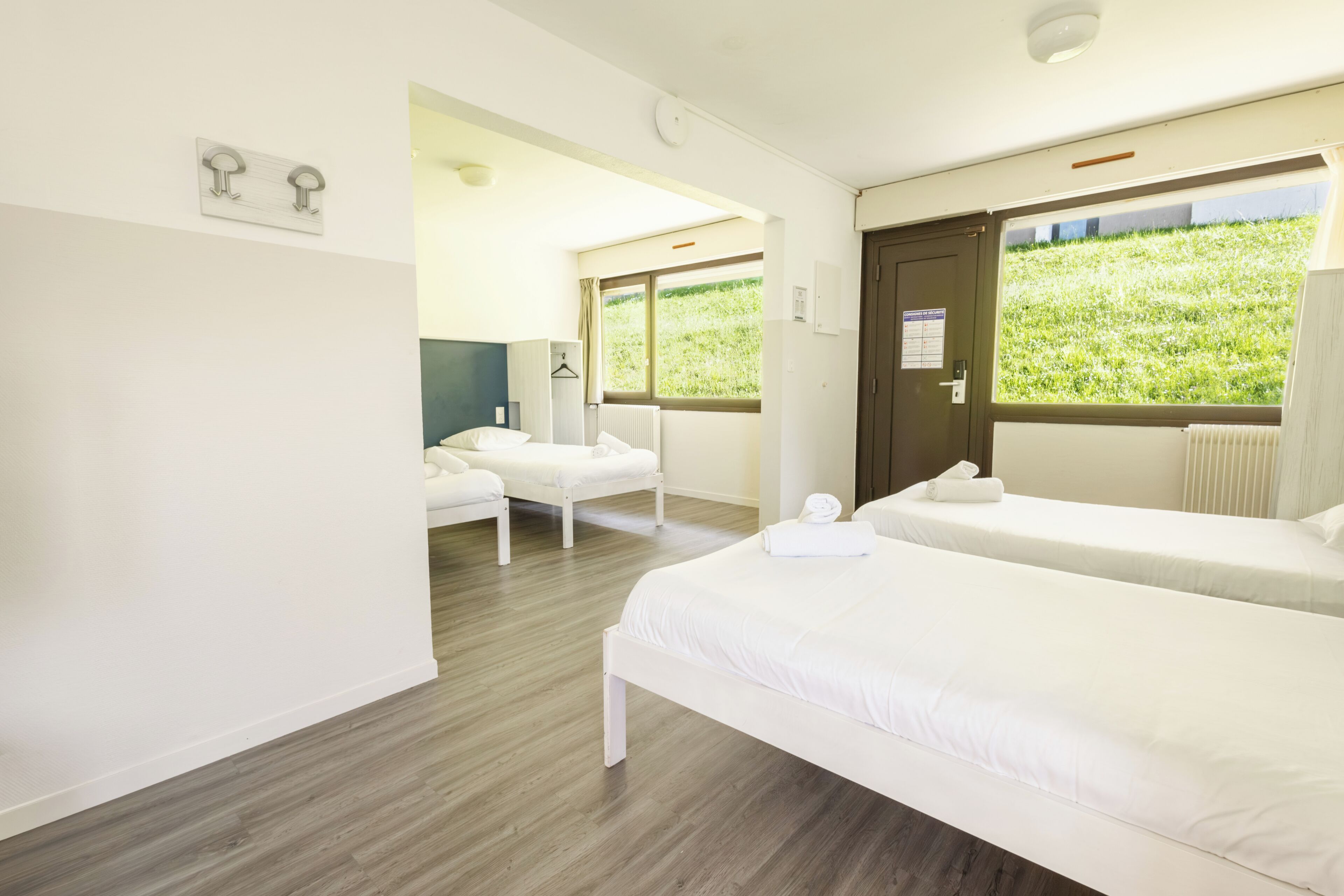 Una habitación de hotel con dos camas, un área de estar y un ventanal con vistas a zonas verdes.