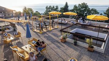 Una terraza en la azotea con mobiliario exterior, un área de juegos para niños y vistas al agua.