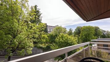Een balkon met uitzicht op bomen en een gebouw op de achtergrond.
