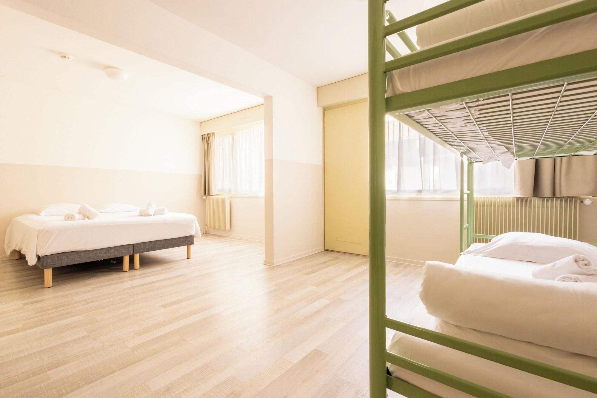 Habitación de hotel con literas, una cama individual y un ventanal grande.
