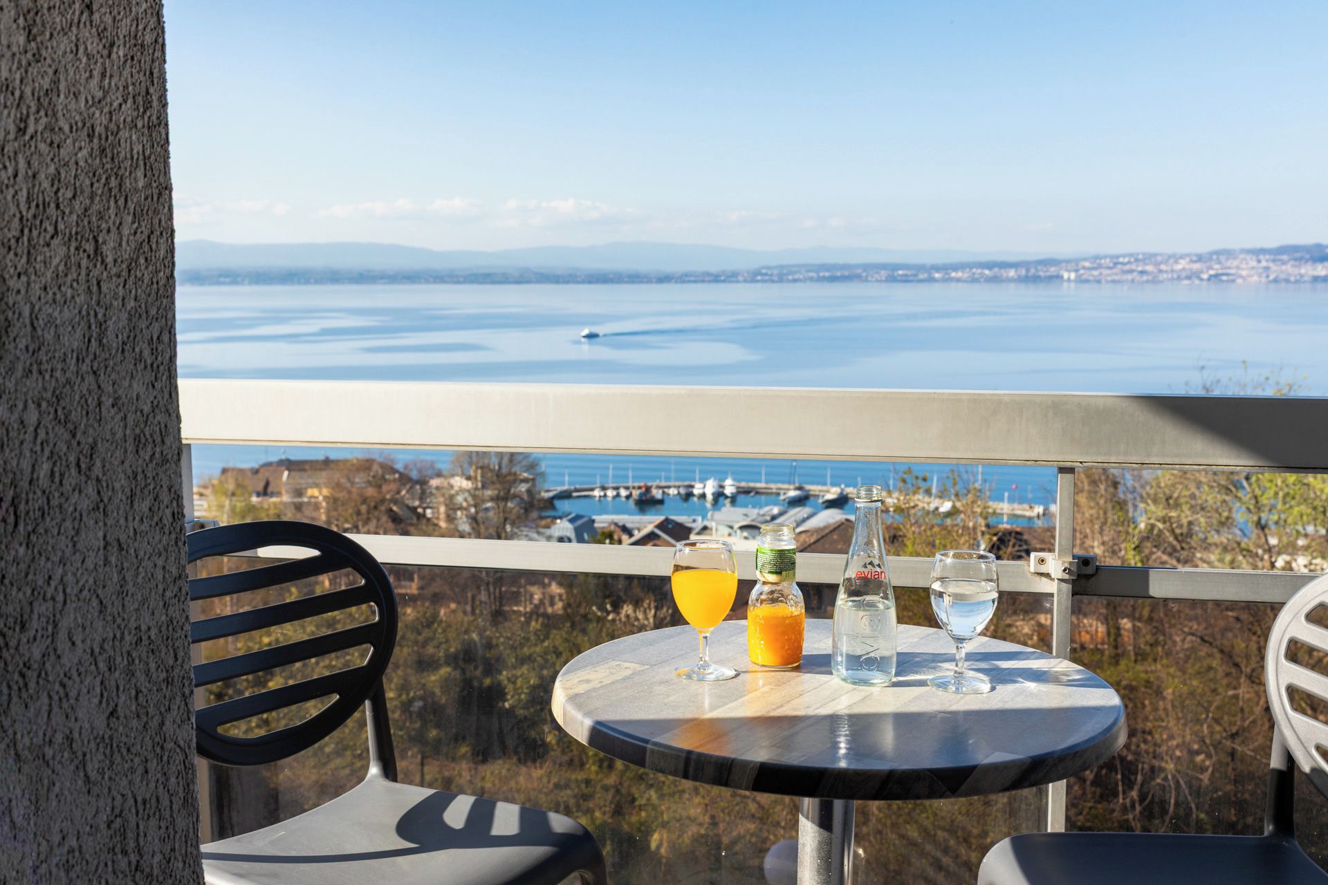 A balcony with a table set for two, overlooking a marina and a body of water.