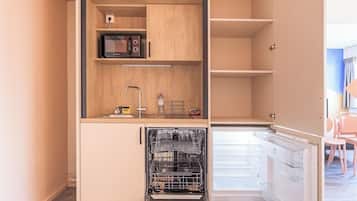 A compact kitchen with a dishwasher, microwave, and a small sink.