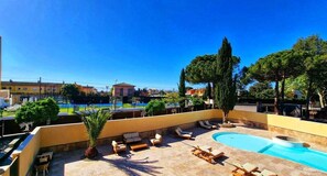 A rooftop pool area with lounge chairs and a swimming pool, surrounded by trees and buildings in the background. - Boutique Hotel Comtal Empuries (Castello d'Empuries)