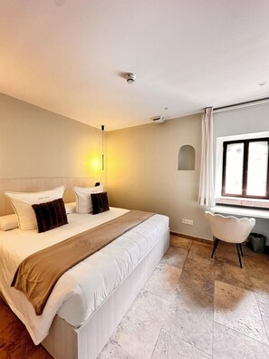 A modern bedroom with a large bed, a desk, and a chair. - Boutique Hotel Comtal Empuries (Castello d'Empuries)