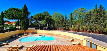Un área de piscina con sillones de descanso y una piscina circular.