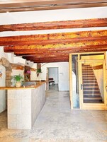 Un área de recepción con mostrador de piedra, vigas de madera, una escalera y un banco.