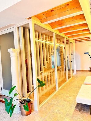 A room with a wooden ceiling, a glass partition, and a white table. - Boutique Hotel Comtal Empuries (Castello d'Empuries)