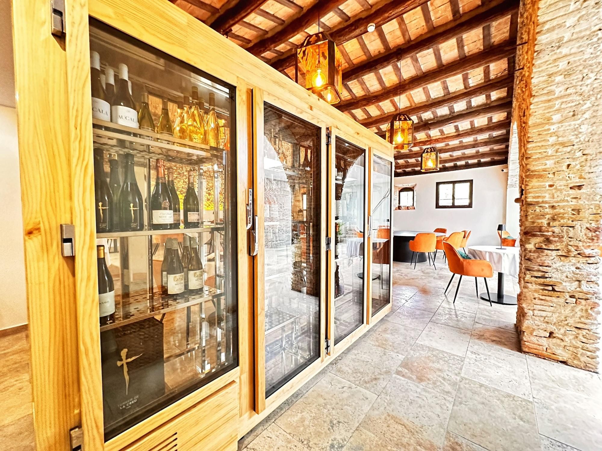 Una bodega de madera con puertas de cristal, una pared de piedra y un área de comedor con sillas naranjas.