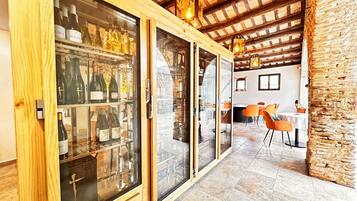 Una bodega de madera con puertas de cristal, una pared de piedra y un área de comedor con sillas naranjas.