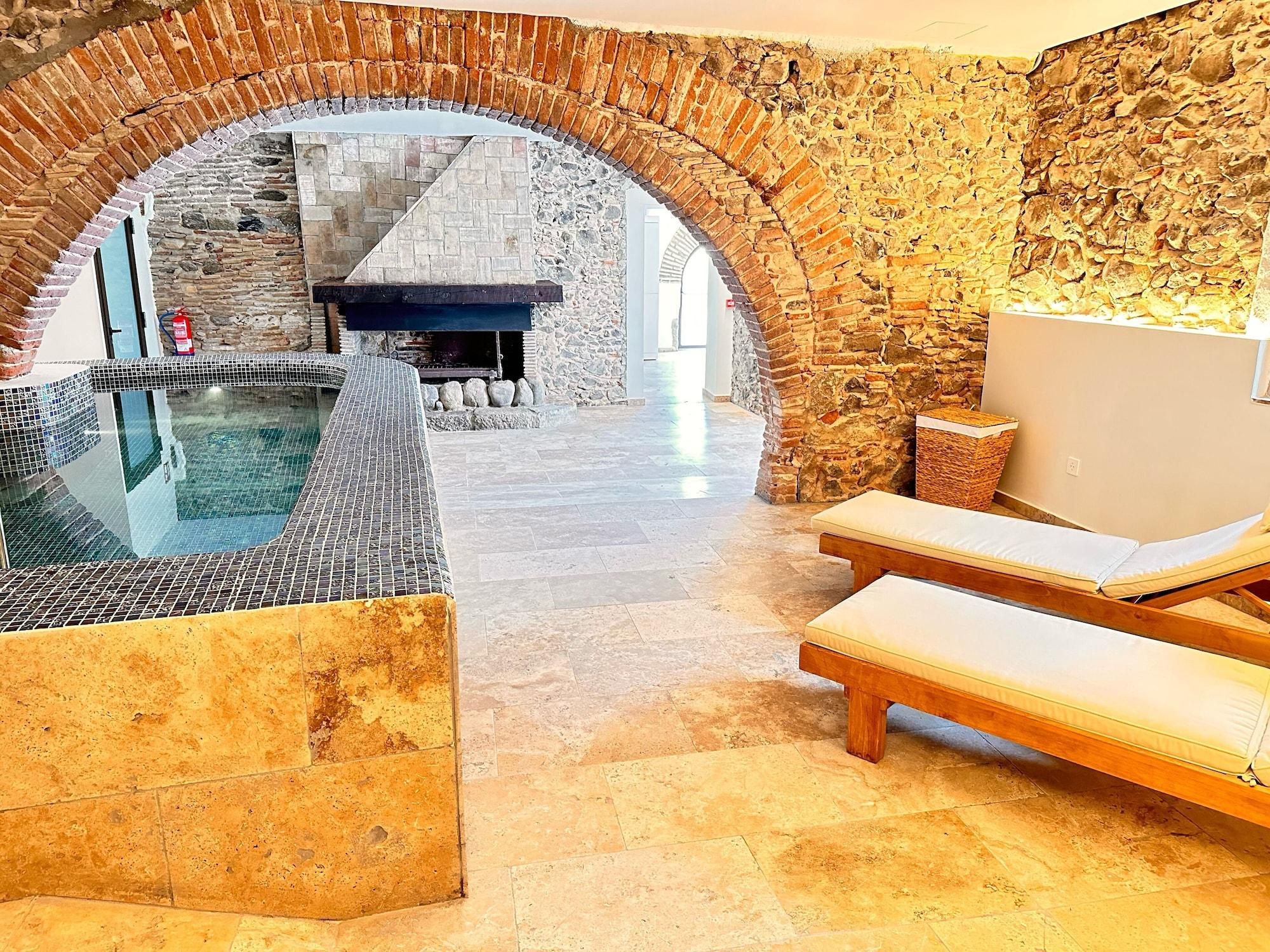 Un espace de bien-être doté d’une arche en pierre, d’un jacuzzi et d’un fauteuil de relaxation.