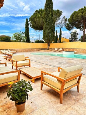 Zona junto a la piscina con sillones de descanso y una piscina pequeña.