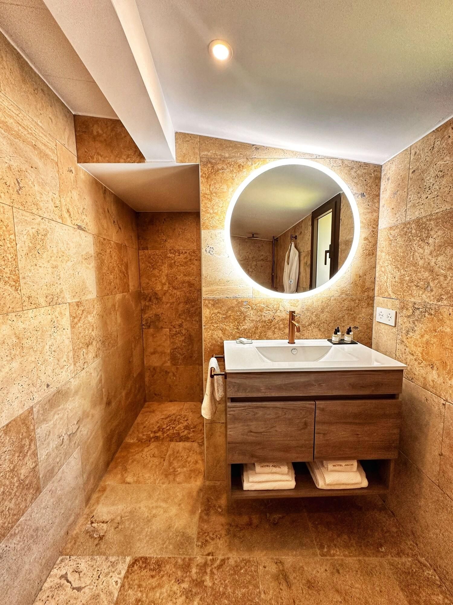 A modern bathroom with a large mirror, a sink, and a shower.