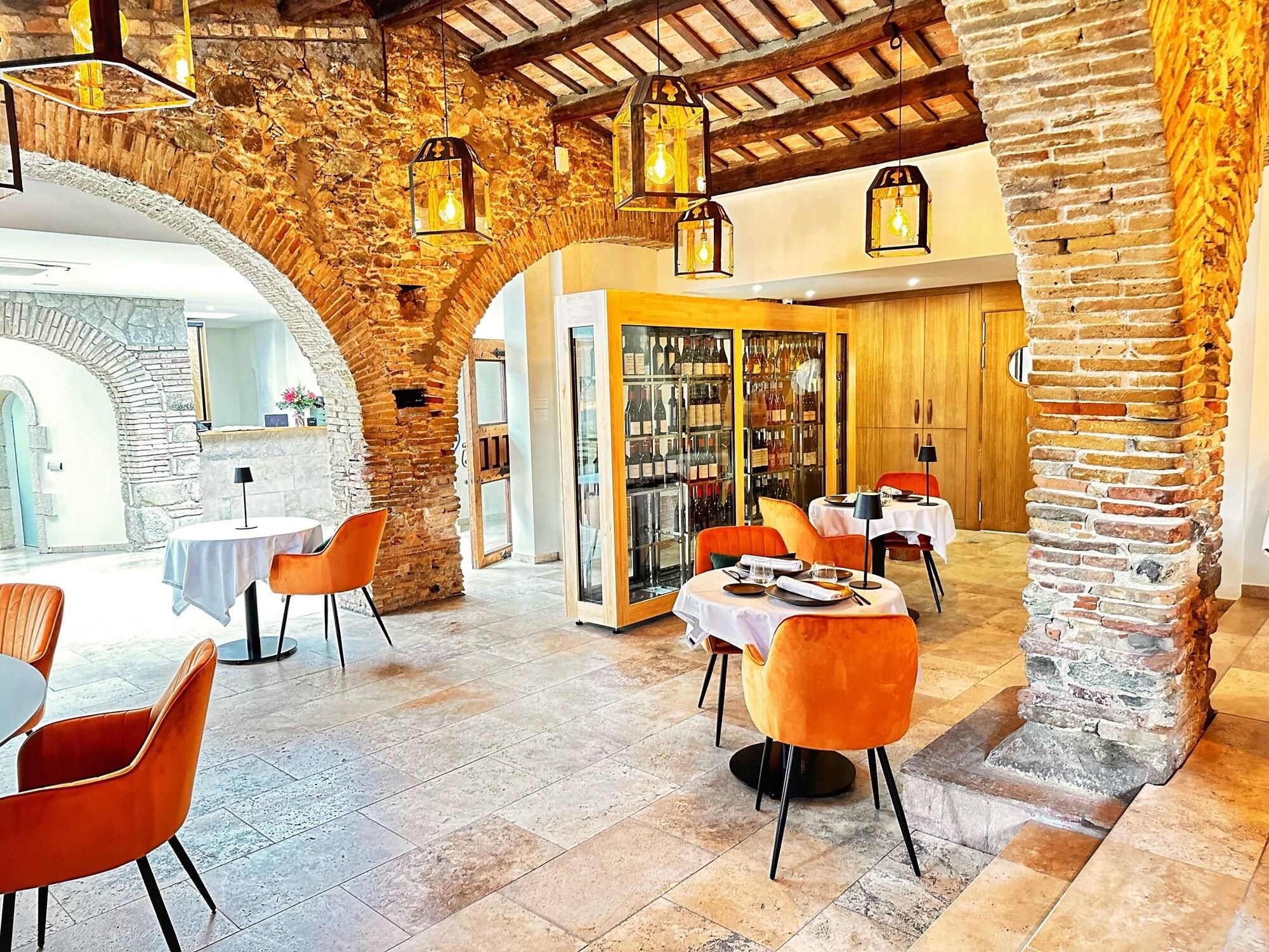 A restaurant with stone arches, wooden beams, and orange chairs.