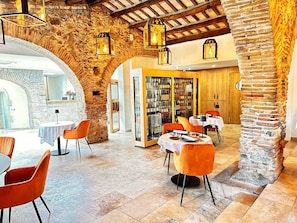 Un restaurant d'arcs de pedra, bigues de fusta i cadires taronja.